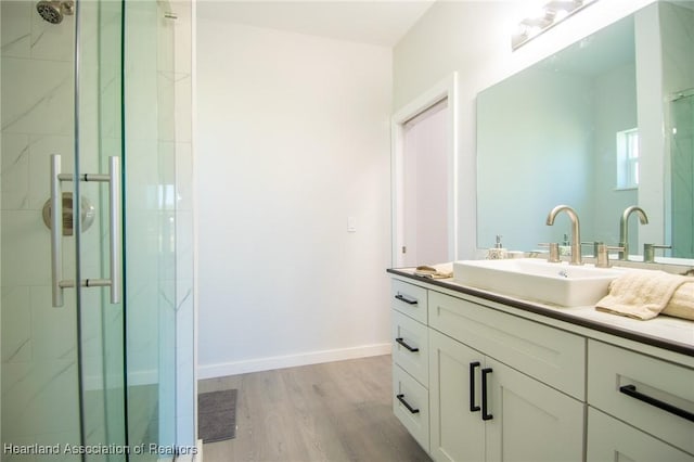 full bath featuring vanity, a shower stall, wood finished floors, and baseboards