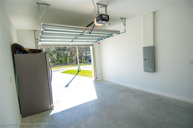 garage featuring electric panel, a garage door opener, freestanding refrigerator, and baseboards