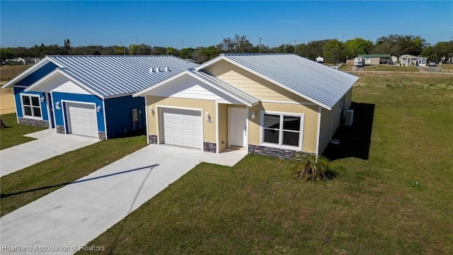 view of front of property with stone siding, concrete driveway, a front yard, an attached garage, and metal roof