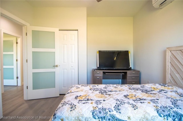 bedroom featuring a wall unit AC, wood finished floors, and a closet