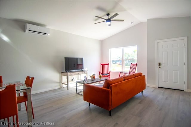 living area featuring wood finished floors, a ceiling fan, a wall unit AC, and vaulted ceiling