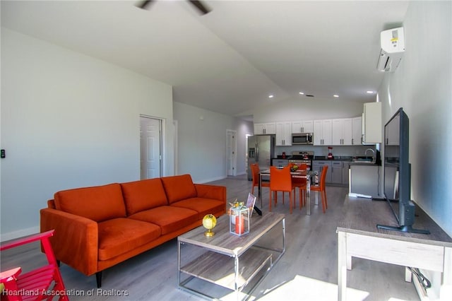 living room featuring baseboards, light wood-style floors, vaulted ceiling, and a wall mounted AC