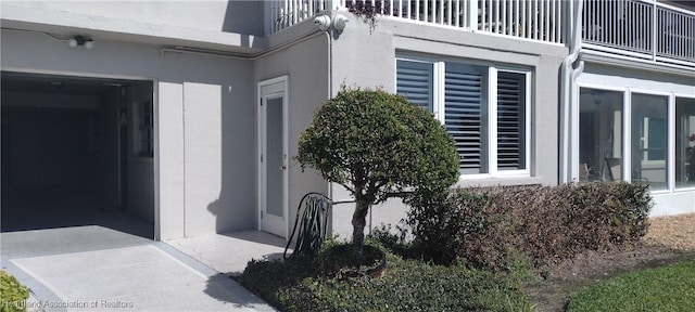 view of exterior entry featuring a balcony and stucco siding