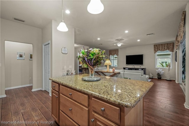 kitchen featuring light stone countertops, pendant lighting, dark hardwood / wood-style floors, and a kitchen island