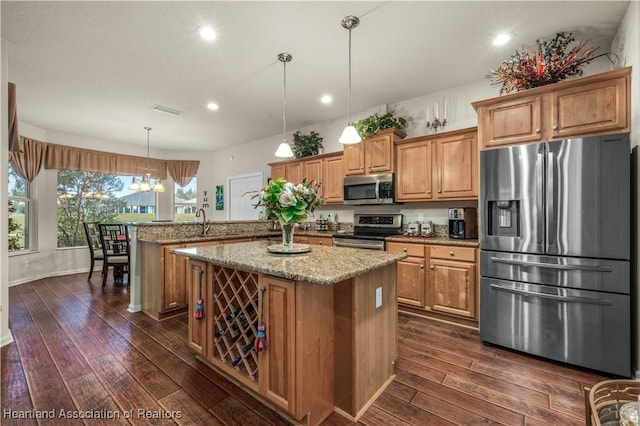 kitchen with hanging light fixtures, a kitchen island, kitchen peninsula, dark wood-type flooring, and stainless steel appliances