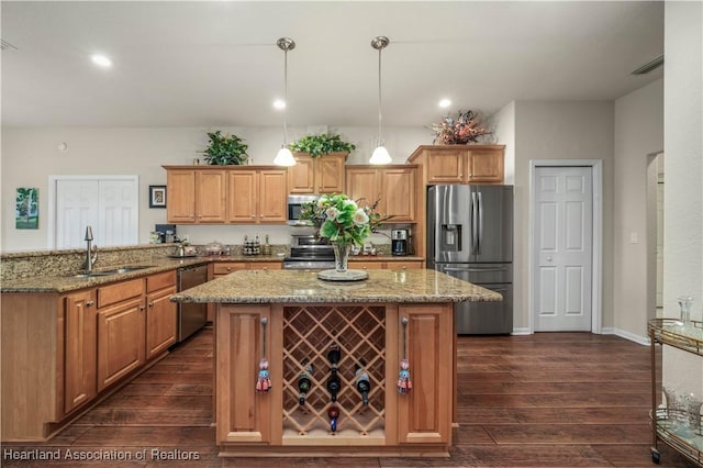 kitchen with light stone countertops, pendant lighting, stainless steel appliances, sink, and kitchen peninsula