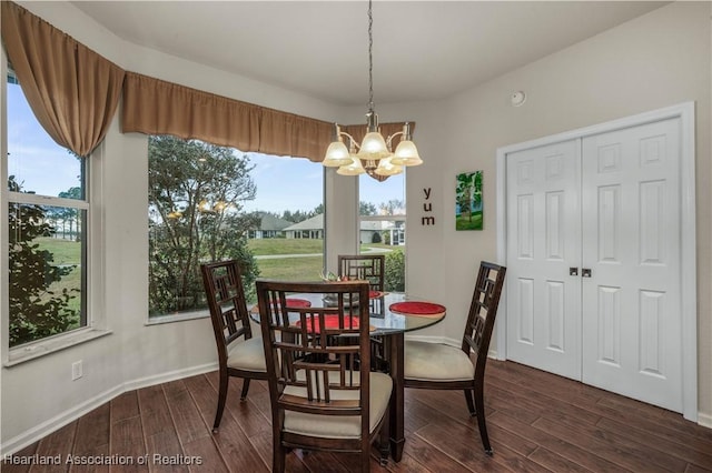 dining area featuring dark wood-type flooring and a notable chandelier