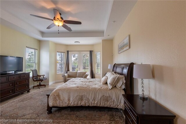 bedroom with multiple windows, a raised ceiling, and ceiling fan