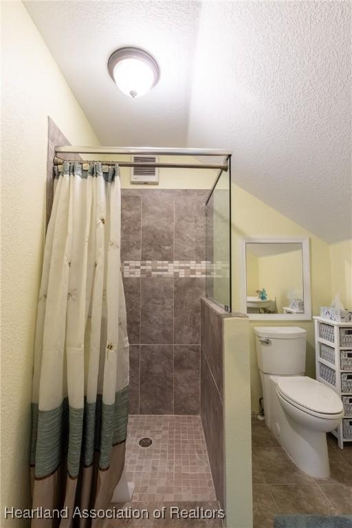 bathroom featuring a shower with curtain, a textured ceiling, and toilet