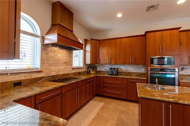 kitchen with light stone countertops, custom range hood, stainless steel appliances, and sink