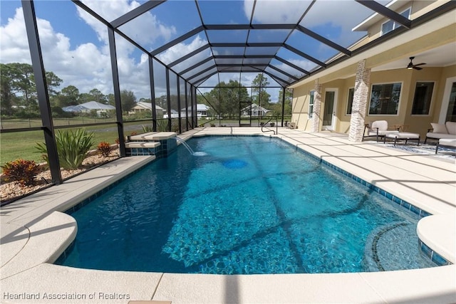 view of pool with glass enclosure, pool water feature, and a patio area