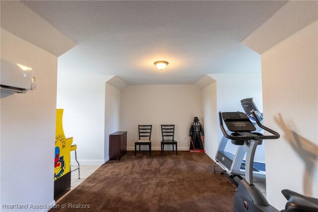 exercise room featuring dark colored carpet, a textured ceiling, vaulted ceiling, and a wall unit AC