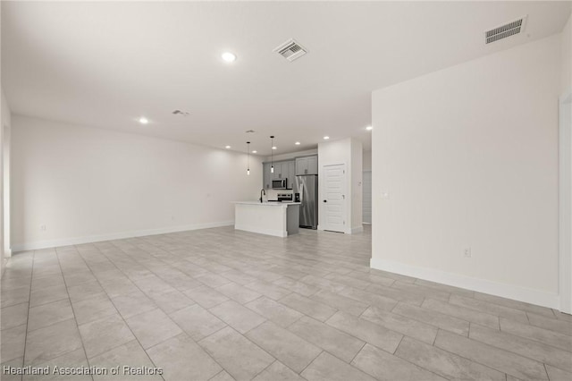 unfurnished living room featuring recessed lighting, a sink, and baseboards