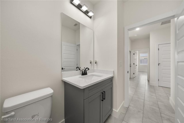 bathroom featuring vanity, tile patterned flooring, toilet, and baseboards