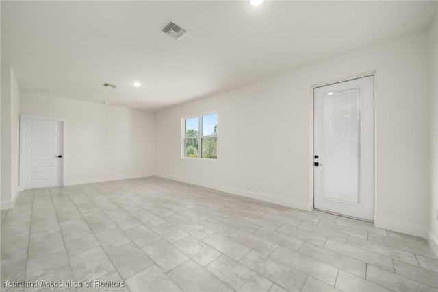 spare room with recessed lighting and baseboards
