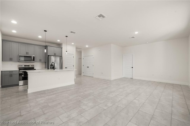 kitchen with appliances with stainless steel finishes, gray cabinets, recessed lighting, open floor plan, and light countertops
