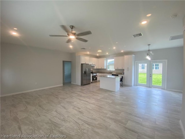 kitchen featuring stainless steel appliances, sink, white cabinets, a center island, and hanging light fixtures