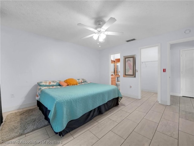 bedroom featuring ceiling fan, a walk in closet, a textured ceiling, and ensuite bathroom