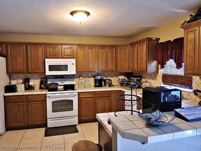 kitchen featuring tasteful backsplash, brown cabinetry, tile countertops, and white appliances