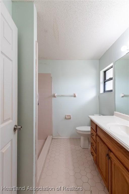 bathroom featuring vanity, a textured ceiling, toilet, and a shower