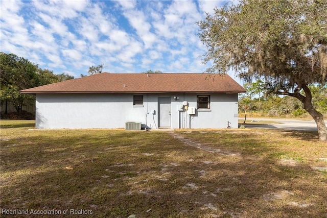 rear view of property with central AC unit and a yard