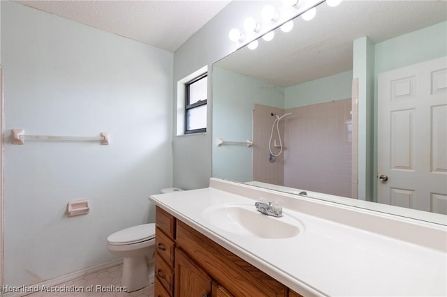 bathroom with tile patterned flooring, tiled shower, vanity, a textured ceiling, and toilet