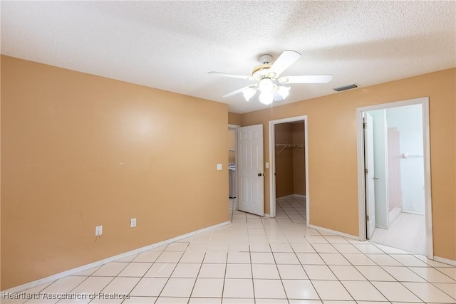 unfurnished bedroom featuring ensuite bathroom, a spacious closet, a textured ceiling, a closet, and ceiling fan