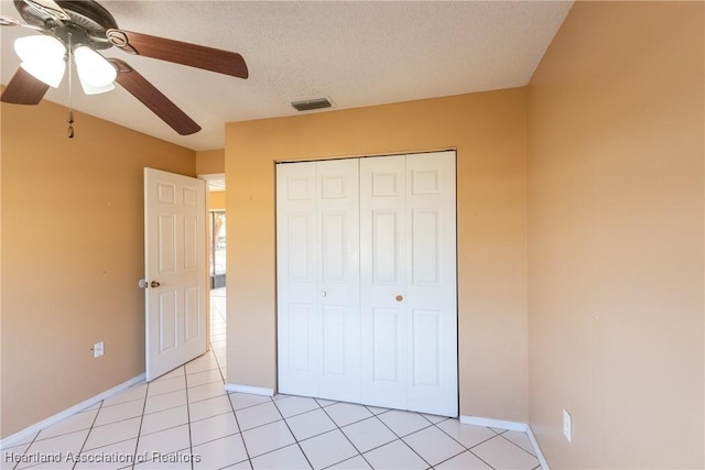 unfurnished bedroom featuring ceiling fan, a textured ceiling, a closet, and light tile patterned floors