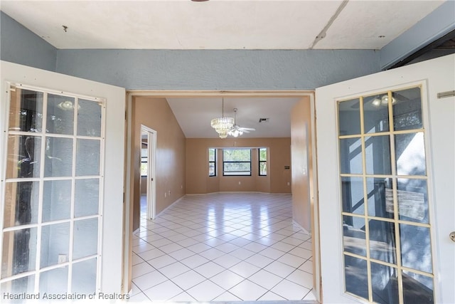 tiled spare room featuring lofted ceiling and a chandelier