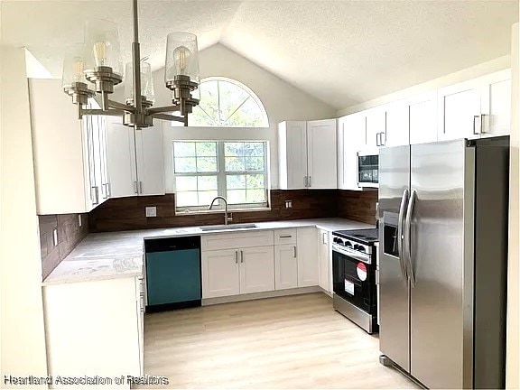 kitchen with backsplash, white cabinetry, sink, and stainless steel appliances