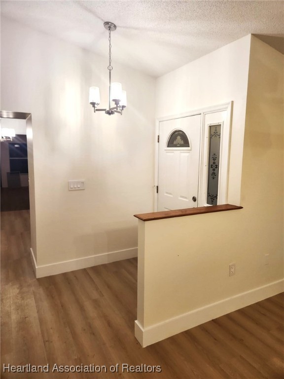 entryway featuring dark hardwood / wood-style flooring, a textured ceiling, and an inviting chandelier