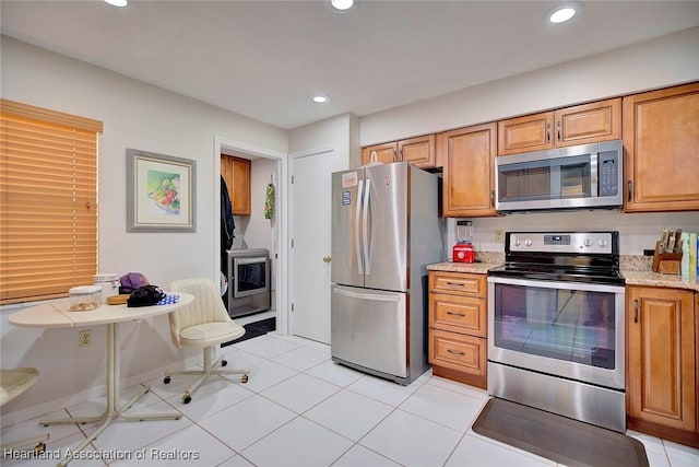 kitchen with light stone countertops, appliances with stainless steel finishes, and light tile patterned floors