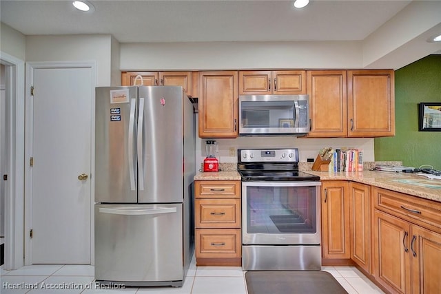 kitchen featuring stainless steel appliances, light stone countertops, and light tile patterned floors