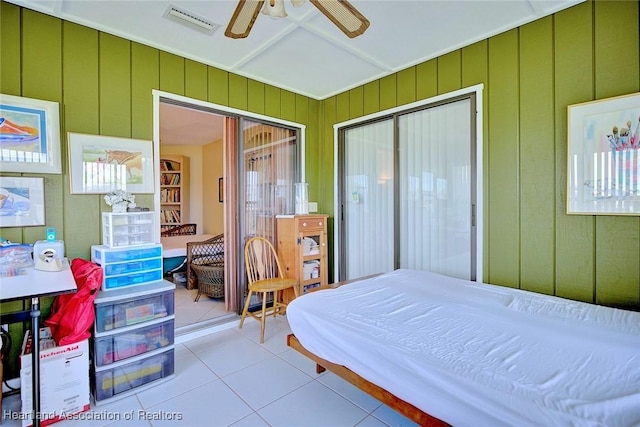 tiled bedroom featuring wooden walls, a closet, and ceiling fan