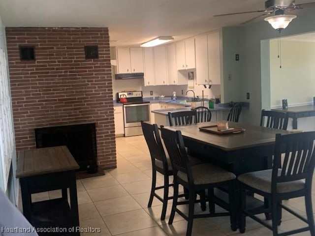 dining area with a ceiling fan, light tile patterned flooring, and a fireplace