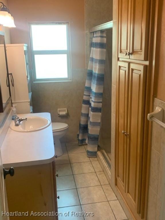 full bath with vanity, toilet, tile patterned floors, tile walls, and a stall shower