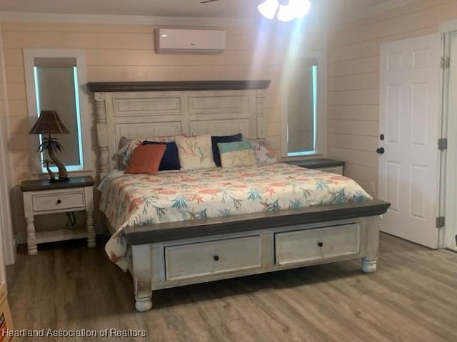 bedroom with an AC wall unit and wood finished floors