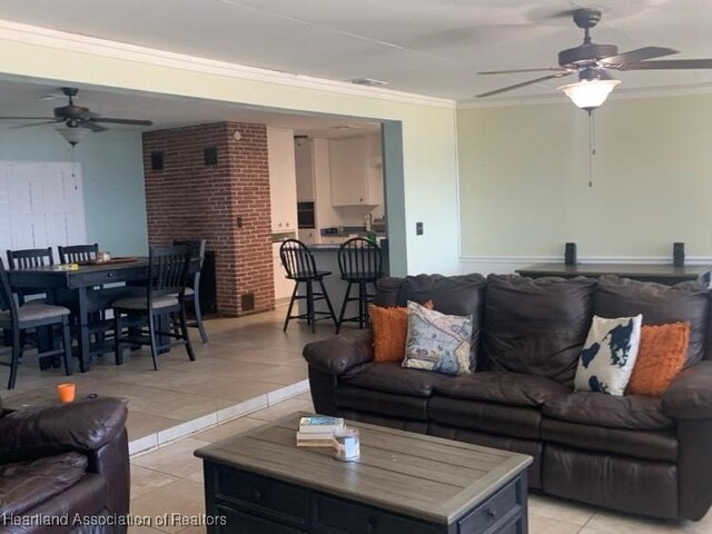 living area with crown molding, ceiling fan, and light tile patterned floors