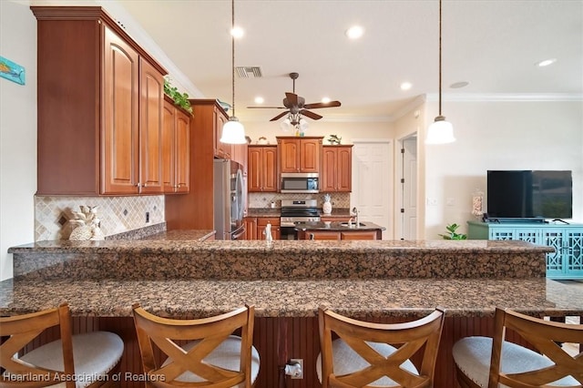 kitchen with a kitchen bar, tasteful backsplash, decorative light fixtures, ornamental molding, and stainless steel appliances