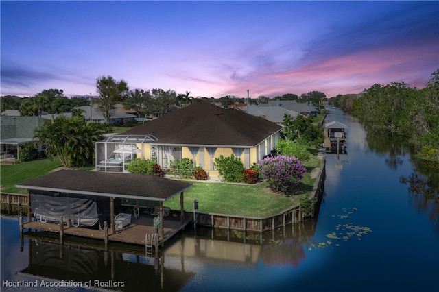 view of dock with a yard, a lanai, and a water view