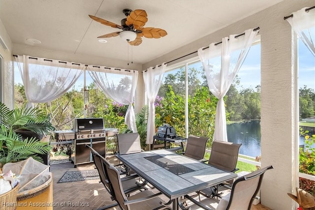 sunroom / solarium featuring a water view and ceiling fan