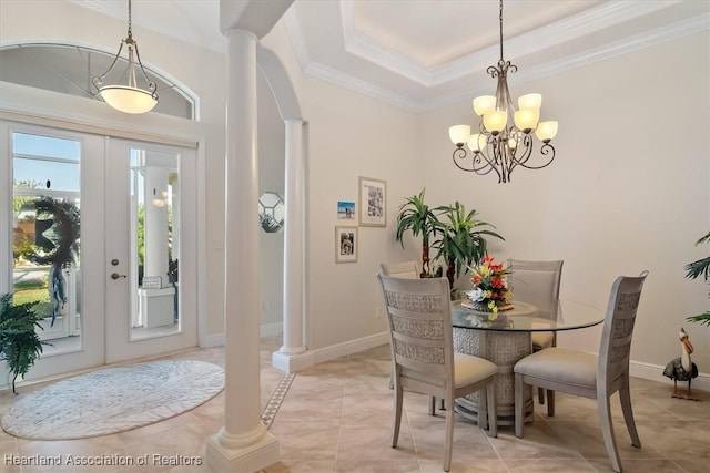 tiled dining space featuring french doors, crown molding, a raised ceiling, a notable chandelier, and decorative columns