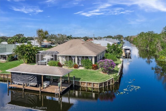 back of house featuring a water view, glass enclosure, and a lawn