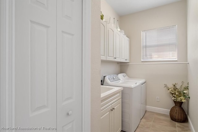 washroom featuring light tile patterned floors, washer and clothes dryer, and cabinets