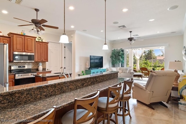 kitchen with a kitchen bar, tasteful backsplash, decorative light fixtures, ornamental molding, and appliances with stainless steel finishes