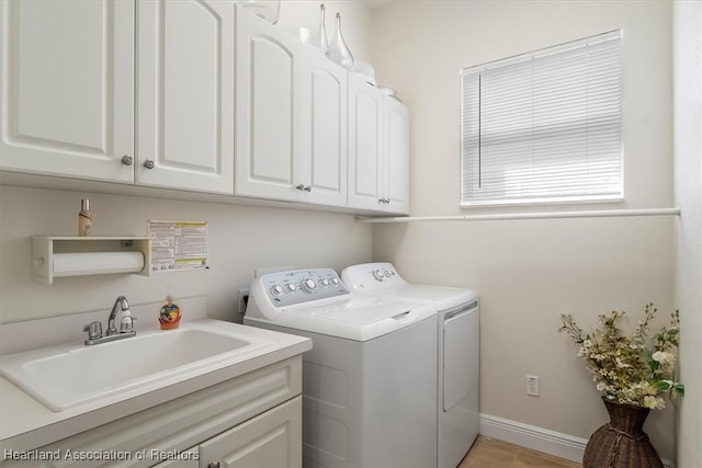 clothes washing area featuring sink, cabinets, and independent washer and dryer