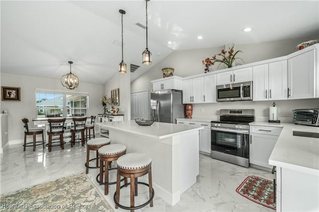 kitchen with a center island, white cabinets, hanging light fixtures, and appliances with stainless steel finishes