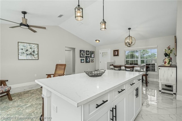 kitchen featuring a center island, ceiling fan with notable chandelier, vaulted ceiling, decorative light fixtures, and white cabinetry