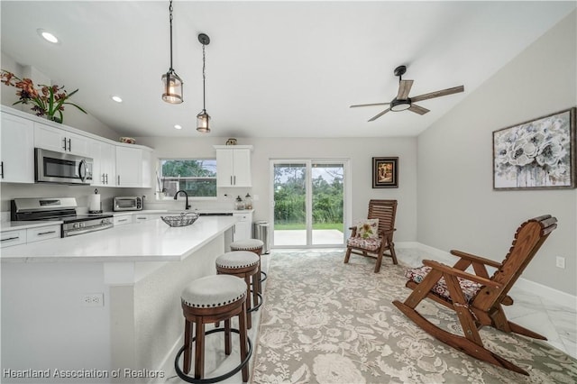 kitchen featuring white cabinetry, hanging light fixtures, a kitchen island, and stainless steel appliances