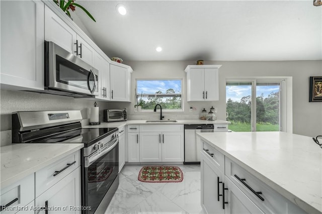 kitchen with white cabinetry, light stone countertops, sink, and stainless steel appliances